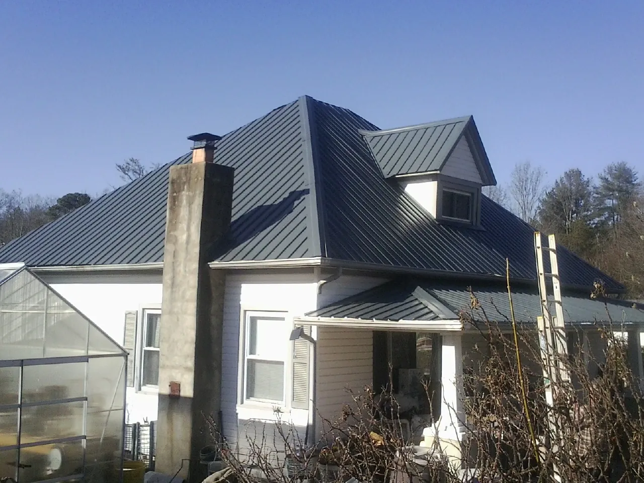 Dark blue standing seam metal roof on a white farmhouse with dormer — Slate & Tile Roof Repair by Roofing Brothers in Martins Ferry