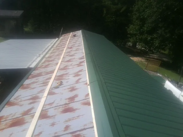 Old rusted panels beside newly installed green metal roofing — Wind Damage Roof Repair by Roofing Brothers in Martins Ferry