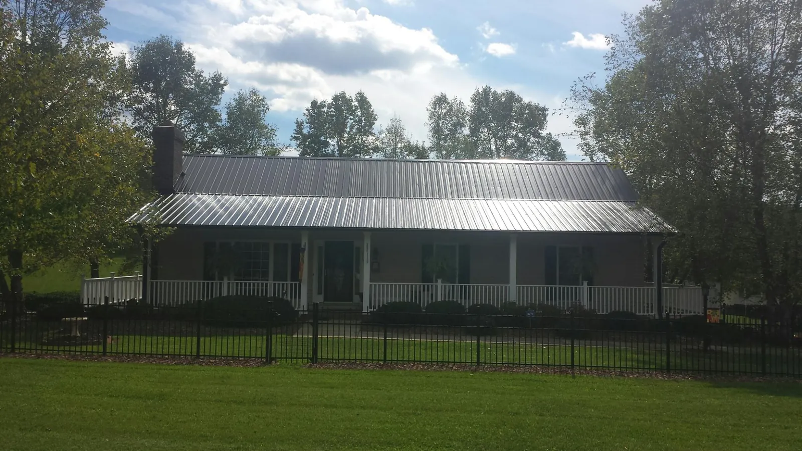 Gray metal roof on a brick ranch with a full width front porch — Gutter Guard Installation work by our crew in Martins Ferry