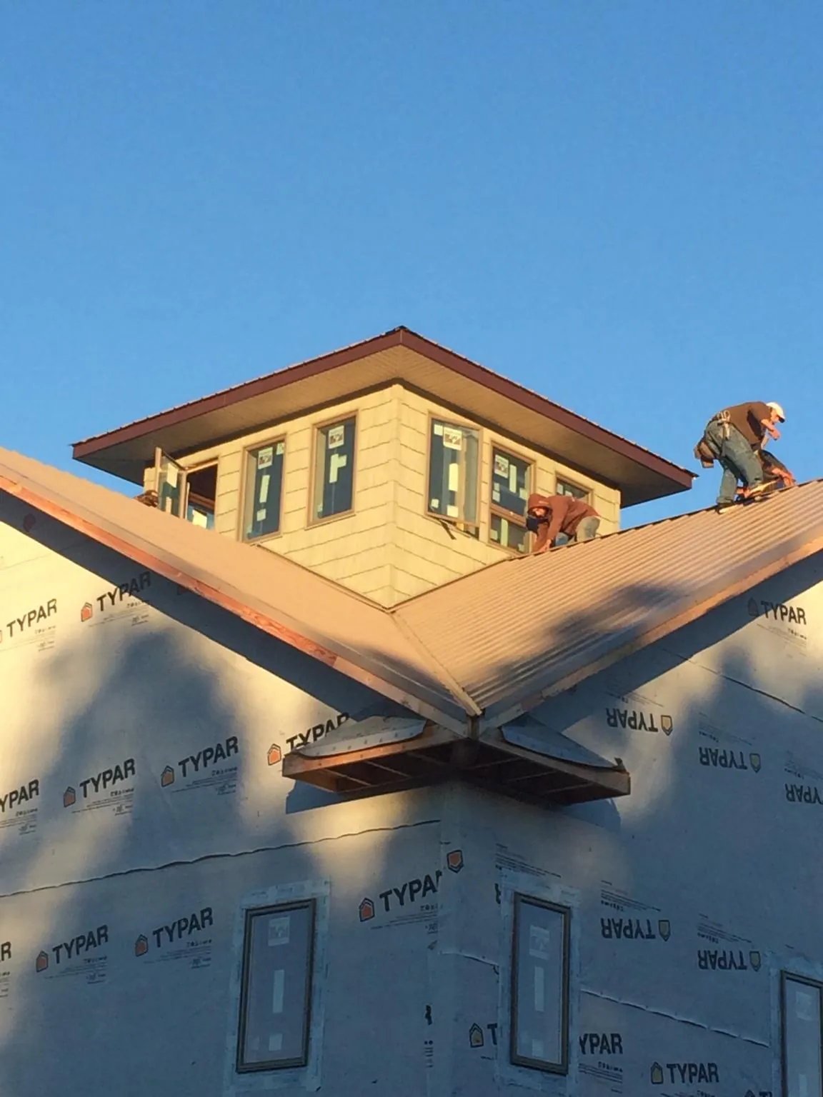 Roofers working around a rooftop cupola on a new metal roof at sunset — Roof Waterproofing in Martins Ferry by Roofing Brothers